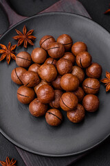 Delicious roasted macadamia nuts in shell on a dark textured background