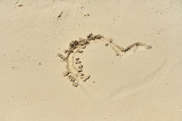 A heart painted on the sand and half washed away by a wave.