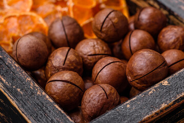 Delicious roasted macadamia nuts in shell on a dark textured background