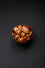 Pecan nuts in shell and peeled in a wooden round bowl