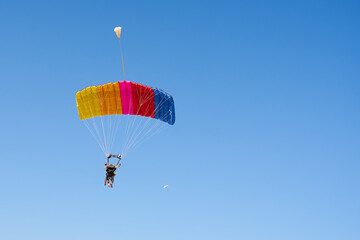 Colorful parachute against a clear blue sky.