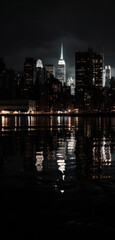 Fototapeta na wymiar night cityscape in the distance with bright lighting over the water. reflection in the water. vertical frame.Generative AI