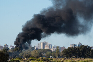 Open-air landfill fire that pollutes the environment and a city in the background.