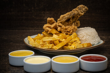 Pollo broster con arroz y ensalada y al rededor cremas 