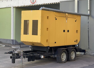 Diesel generator of electricity, trailer platform on wheels. It stands on the street connected to an office building.