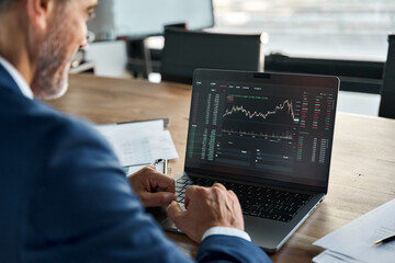 Stock market Investor analyst broker analyzing financial trade crypto stockmarket exchange platform digital chart data on computer screen thinking of investing analytic risk. Over shoulder view.