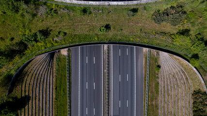 Top down aerial empty highway interrupted by wildlife crossing ecoduct corridor bridge for animals...