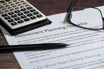 Retirement planning checklist with calculator, glasses and pencil focuus on words retirement...