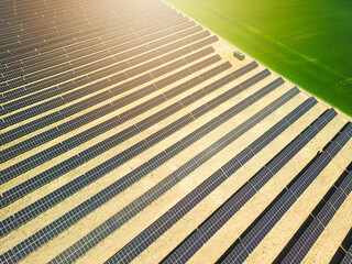 Solar panels among a green field or meadow. Solar energy or renewable energy. Photovoltaic panels view from a drone or from a bird's eye view
