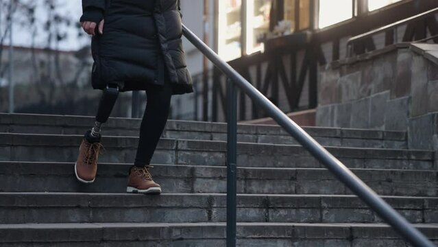 Staircase descent, Prosthetic leg, Descending challenge. City street is accessed by man with disability and prosthetic leg descending stairs.