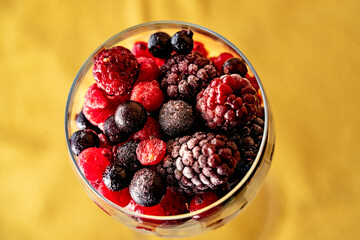 top view of a glass cup with a lot of blueberries and strawberries