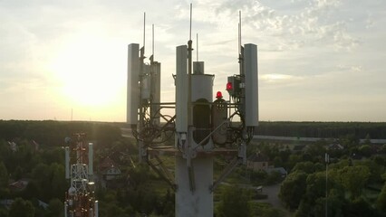 Drone flying around cell tower antennas, base station transmitting 5g, 4g signals in countryside.