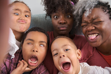 Happy african horizontal extended family taking a selfie making funny faces at home.