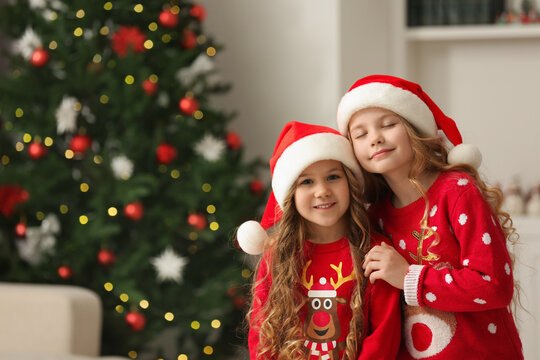 Cute little girls near Christmas tree at home. Space for text