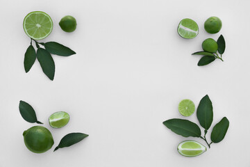 Whole and cut fresh limes with leaves on white background, flat lay. Space for text
