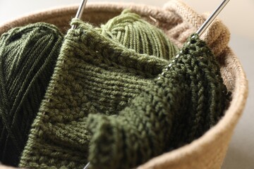 Fototapeta na wymiar Green knitting, needles and soft yarns on light background, closeup