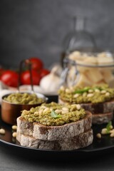 Tasty bruschettas with pesto sauce and nuts on plate, closeup