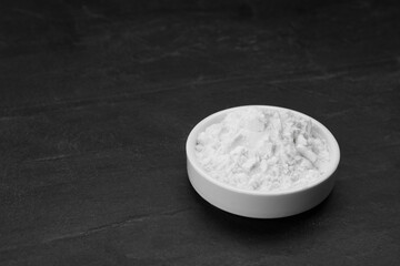 Bowl of natural starch on black table, space for text