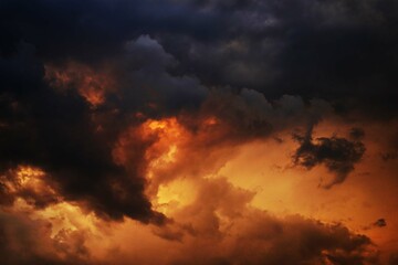 Yellow orange red blue black sky with clouds. Dark cloudy dramatic ominous skies background. Fire,...