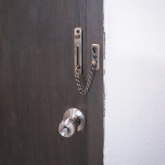 Close up chain lock and doorknob on brown door. Interior detail design. - 604488278