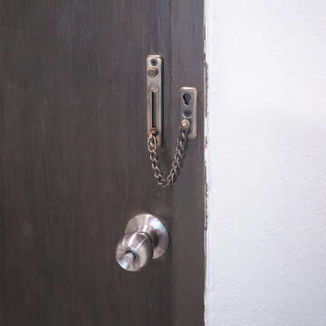 Close up chain lock and doorknob on brown door. Interior detail design.