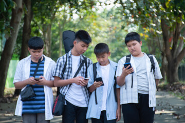 Blurred image of young asian boys are using mobile phone and walking homes afterschool together,...