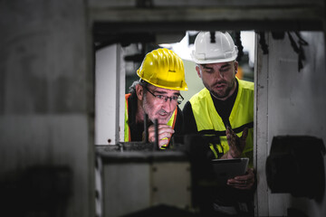 Technicians and engineers check the operation of machinery in the manufacturing plant with a...