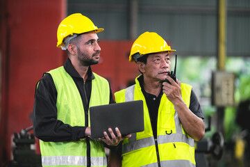 technician, supervisor with a senior foreman holding a walkie-talkie to command or inspect work with a checklist computer The background is an industrial warehouse.