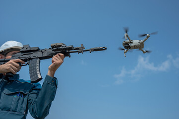 Fototapeta na wymiar Caucasian man in a helmet shoots a flying drone with a rifle. 