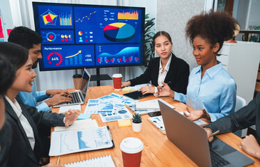 Multiracial analyst team use BI dashboard data to analyze financial report on meeting table. Group of diverse business people utilize data analysis by FIntech for business marketing decision. Concord