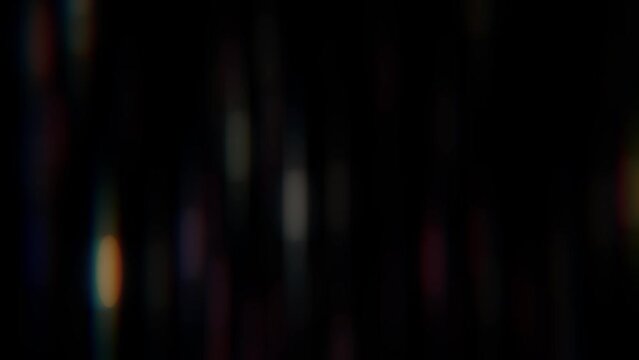 An anamorphic background of light leakage. Vertical spots of light flicker against a black background.