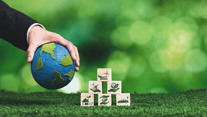 Hand of businessman holding Earth, symbolizing green business utilizing biofuel technology and...