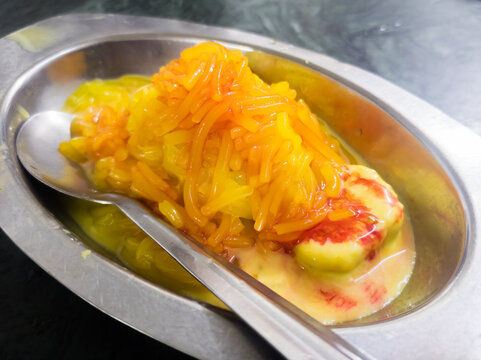 Kesar kulfi with faluda and syrup served on a steel plate and spoon. It is a traditional ice cream in india made of milk and saffron.