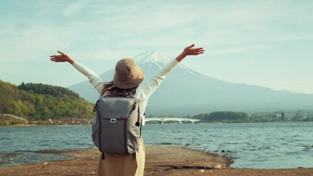 Back view of happy woman traveler enjoying with open arms in mountain Fuji view in bright day, Japan travel vacation, Freedom