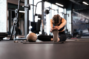 Fototapeta na wymiar Young sporty woman stretching at the gym.