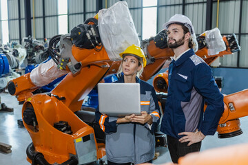 Engineers working robot assembly industry plant in factory using laptop examining condition...