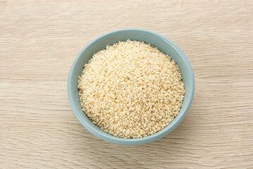 Organic White Sesame Seeds (Sesamum indicum) or Wijen, served in small bowl on wooden background
