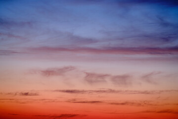 Evening clouds in the sunset sky in the light of the rays of the setting sun