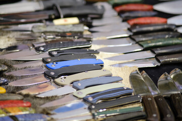 Various military knives are present on the desk, and the store carries blades designed for both military and household functions.