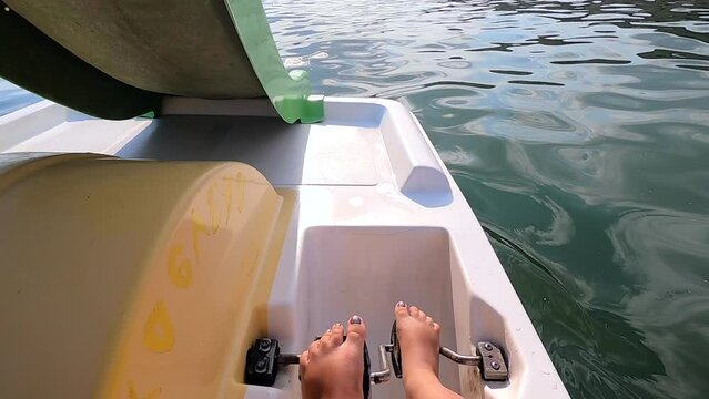 Woman floating on catamaran. Person pedaling with her feet and swimming on catamaran on sea surface with waves on sunny summer day. Active lifestyle recreation leisure sport POV