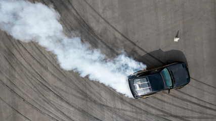 Aerial top view race car drifting on speed track, Professional driver drifting car on race track with smoke, Black tire tracks skid on asphalt road, Wheel tire tracks background. © Kalyakan