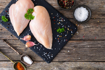 Fresh raw chicken breasts on cutting board with spices on wooden background

