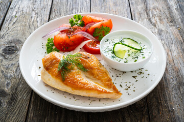 Seared chicken breast and tzatziki on wooden table