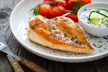 Seared chicken breast and  tzatziki on wooden table