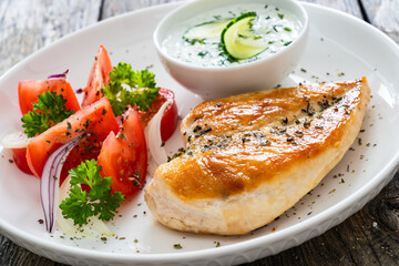 Seared chicken breast and tzatziki on wooden table