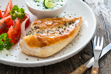 Seared chicken breast and tzatziki on wooden table