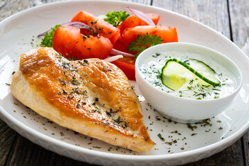 Seared chicken breast and tzatziki on wooden table