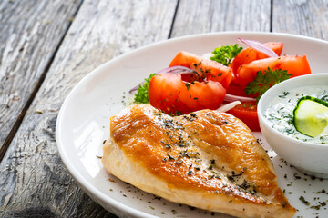 Seared chicken breast and tzatziki on wooden table