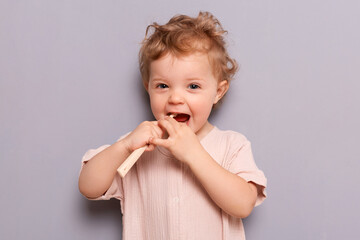 Amazed little girl holding toothbrush isolated on gray background, brushing teeth, taking care of her mouth, oral care, children dental problems.