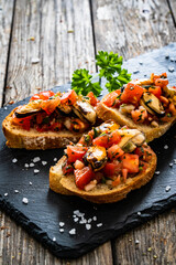Tasty sandwiches - toasted bread with tomatoes and mussels on wooden table
